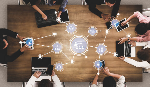 A dynamic business meeting scene showcasing a diverse team engaged in collaboration around a wooden table, utilizing technology and data visualization for productive discussions. Tessel - Powered by Adobe