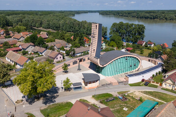 Aerial view of the Church of Our Lady of Refuge standing prominently against the backdrop of the tranquil river and lush greenery, Aljmas, Osijek-Baranja County, Croatia.