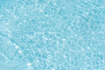 Blue water with ripples on the surface. Defocus blurred transparent blue colored clear calm water surface texture with splashes and bubbles. Water waves with shining pattern texture background.