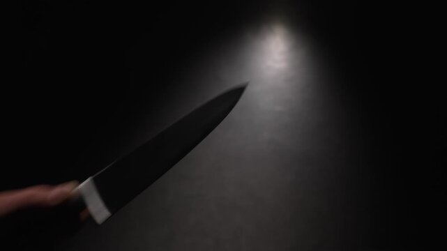 POV, close-up first person view of hand raising sharp knife and stabbing off camera. A serial killer's hand stabbed the victim multiple times at the crime scene.