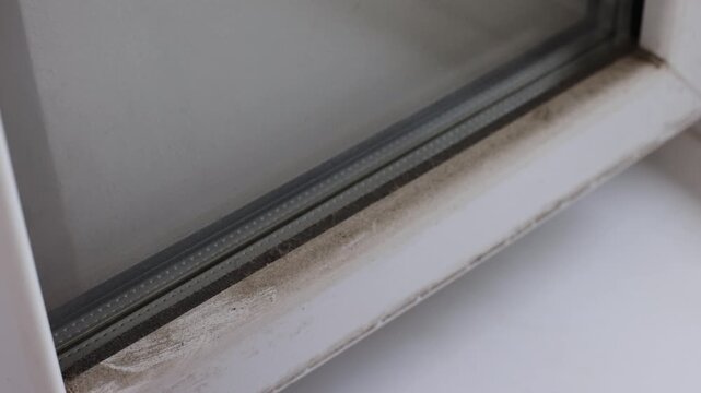 Close-up of a dirty window frame corner with visible dust and stains. Concept of home maintenance, neglected cleaning and household hygiene.