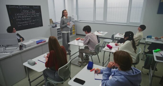 Girl Presents Project to Classmates While Teacher Observes With Interest. Concept Public Speaking, Leadership Development, Teamwork, Project Based Learning in Modern Classroom Environment. Dolly Shot.