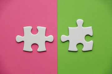 Two puzzle pieces on pink and green background concept of connection teamwork