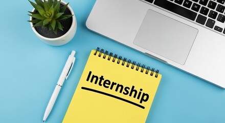 Internship written on a yellow notepad with laptop and pen.