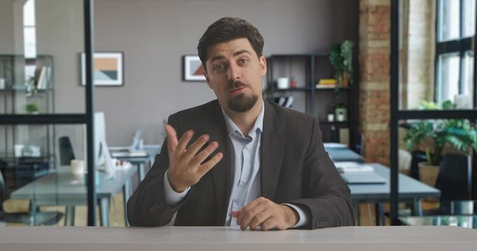A man in a suit sits confidently in a professional live streaming studio setup, ready to broadcast in a modern office setting. A man presents information or news. Ideal for media production.