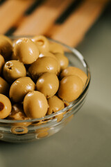 Bowl of green olives arranged on a wooden surface with soft lighting