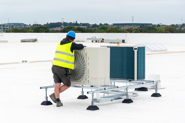 Air conditioning technician inspecting an HVAC system on a rooftop , checking equipment performance and taking maintenance measurements.