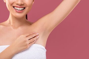 A young lady wrapped in a towel lifts her hand to show her clean armpits. The background is purple, providing a bright and hygienic atmosphere. The focus is on fresh and smooth underarms.