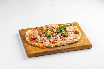 Freshly baked flatbread pizza topped with ham, mushrooms, cheese, and greens on wooden board