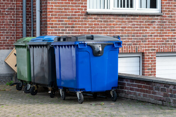  Three large trash bins neatly placed outside a restaurant, ideal for waste management, public hygiene, and outdoor organizationThree
