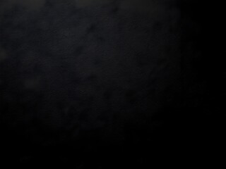 A black, grainy background with a consistent texture, reminiscent of a dark, fine-grained sandpaper or a closely woven fabric under low lighting