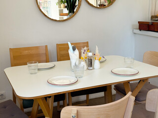 Cozy cafe table set with wooden chairs and minimalist decor. Warm atmosphere, hospitality, and Scandinavian interior design.