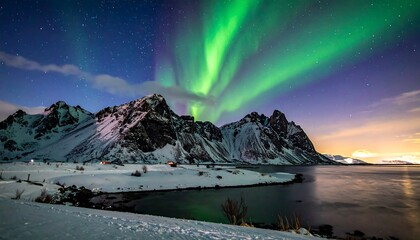Vibrant aurora borealis dances above snow-covered mountains, reflecting on tranquil waters. The dark foreground reveals a coastline with snow