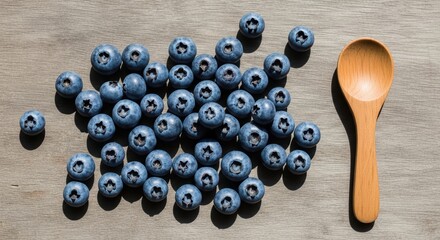Fresh blueberries and wooden spoon on wooden surface