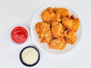 Crispy and crunchy fried chicken in a white plate and mayonnaise sauce in a small black bowl and...