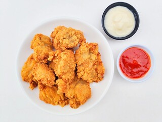Crispy and crunchy fried chicken in a white plate and mayonnaise sauce in a small black bowl and...