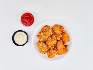 Crispy and crunchy fried chicken in a white plate and mayonnaise sauce in a small black bowl and...