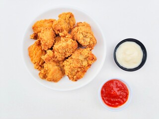 Crispy and crunchy fried chicken in a white plate and mayonnaise sauce in a small black bowl and...