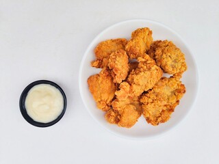 Crispy and crunchy fried chicken in a white plate and mayonnaise sauce in a small black bowl on a...