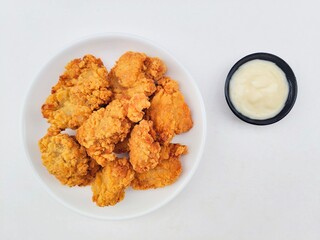 Crispy and crunchy fried chicken in a white plate and mayonnaise sauce in a small black bowl on a...