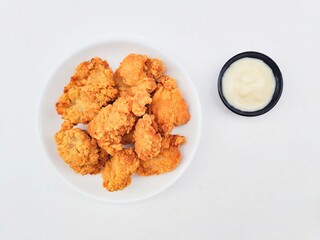 Crispy and crunchy fried chicken in a white plate and mayonnaise sauce in a small black bowl on a...