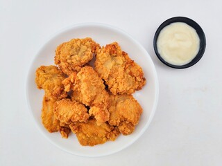 Crispy and crunchy fried chicken in a white plate and mayonnaise sauce in a small black bowl on a...