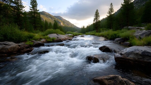 A dynamic river with turbulent whitewater rapids flows through a rocky mountain wilderness at dusk