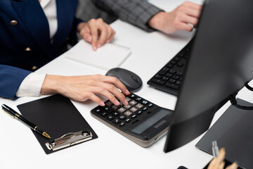 Cropped hands businessman with coworker calculating with calculator manual's financial and accounting report on computer database annual asset report, analyzing expenses and revenue company. Infobahn.