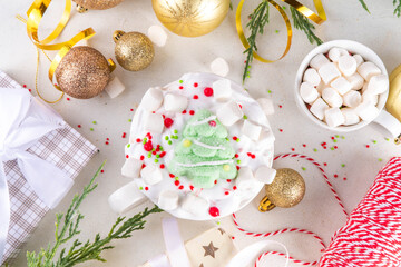 Festive tasty Christmas hot chocolate with whipped cream, marshmallows, sugar sprinkles and Christmas symbol decorations - marshmallow  Christmas tree, on festive holiday decorated  background