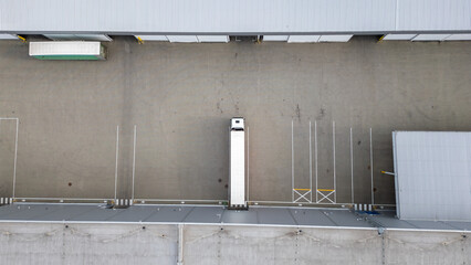 Aerial view reveals a truck at a loading dock of a warehouse, showing logistical operations.