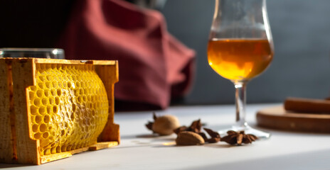 High-quality photo with shallow depth of field focusing on natural honeycomb. Blurred background shows whiskey and spices. Organic food texture, natural sweetener, or premium beekeeping product