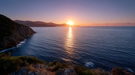 Golden sunset over a calm sea illuminating a rugged coastline and vibrant twilight sky