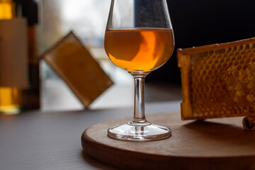 Elegant glass of amber whiskey served with natural honeycomb on rustic wooden stand. Concept of whiskey tasting, honey-flavored spirits. Premium alcoholic beverage with organic honey cells