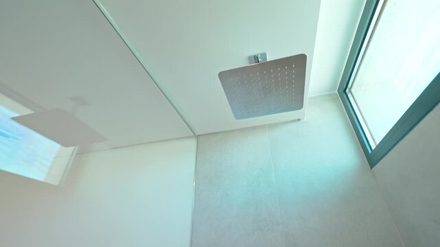 Sequential video capturing professional shower head installation in minimalist white tiled bathroom, transforming empty space into finished setup