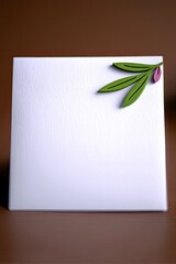 A white card with a decorative olive branch featuring green leaves and a single purple olive is placed on a brown surface.