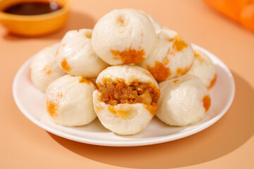 Traditional Chinese Xiaolongbao Steamed Dumplings with Orange Filling on White Plate