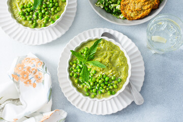 Creamy green pea and broccoli soup garnished with fresh peas is paired with crispy zucchini pancakes and a vibrant salad, creating a healthy and delightful meal