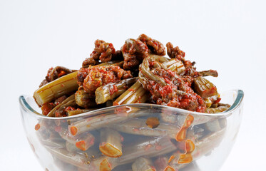 Transparent glass bowl with fern salad with spices close-up on white background.