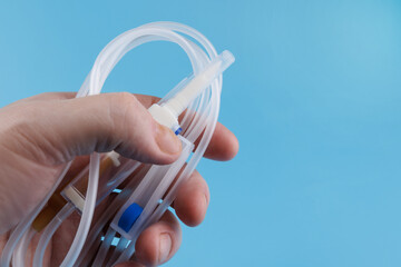 Infusion system in the palm of the hand on a blue background. IV Set Infusion. Intravenous drip system.