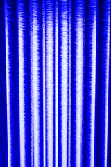 An abstract, vibrant blue background featuring parallel, vertical columns of intense light,...