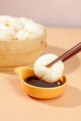 Xiao Long Bao Chinese Soup Dumplings Dunked in Soy Sauce with Chopsticks and Bamboo Steamer
