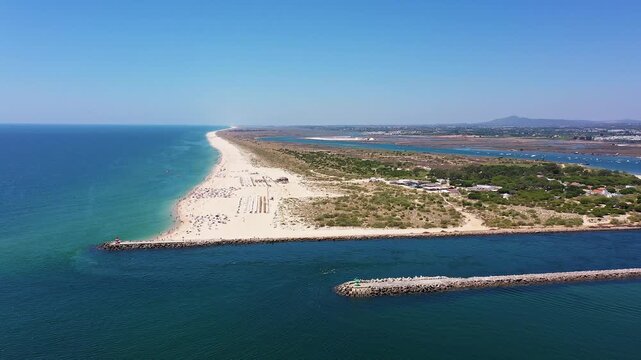 Portugal remote sandbar and dunes along atlantic with pristine shoreline and shallow turquoise waters conservationist walking dunes, habitat vegetation and wetlands of ria formosa reserve visible,