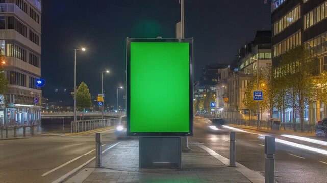 Green screen advertising billboard mockup on a busy city street at night with blurred car lights timelapse.