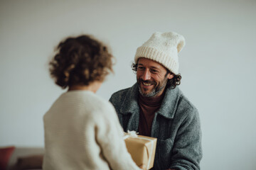 small child joyfully kisses their father who is wearing festive christmas hat in cozy living room setting