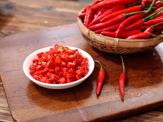 Fresh Red Hot Chili Peppers in Bamboo Basket with Diced Peppers on Wooden Board