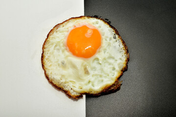 An omelet made from one chicken egg lies on a black and white background.