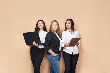 Portrait of three business people. portrait of two young successful business women smiling with joy while standing against neutral background.