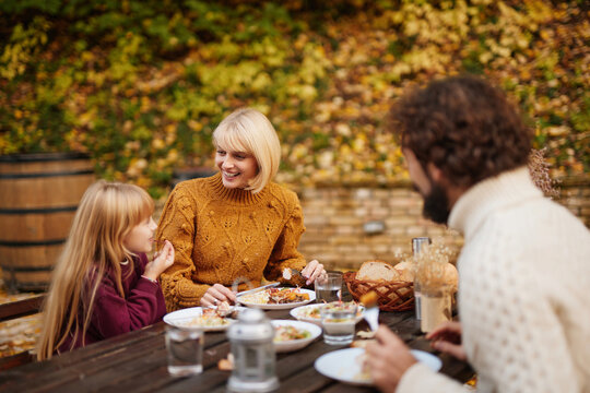 A warm family gathering takes place on a weekend in autumn. They enjoy a meal at a table surrounded by colorful leaves, sharing stories and smiles. - Powered by Adobe