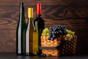 Fototapeta premium Wine bottles and basket of fresh grapes