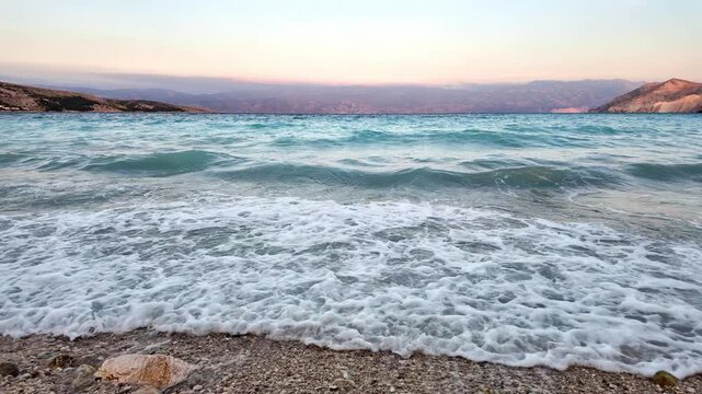 Beautiful waves on a pebble beach at sunset. Ba&scaron;ka, Krk Island, Croatia
